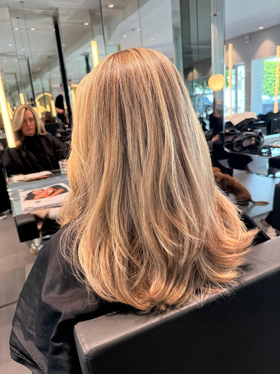 Dieselbe Kundin nachher: glattes, glänzendes blondes Haar, stufig geschnitten
